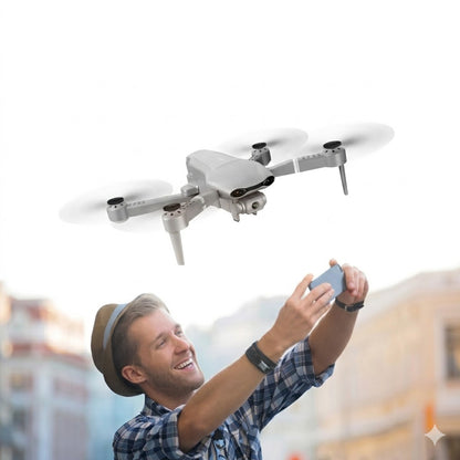 A smiling man in a straw hat and plaid shirt holds up a smartphone to view a real-time Wi-Fi FPV live feed from a flying silver foldable drone with a dual-lens 4K camera. The drone is positioned above him with rotating blades. Blurred warm-toned city buildings are visible in the lower background. This image illustrates the drone's advanced imaging and real-time live-streaming capabilities as described in the product features.